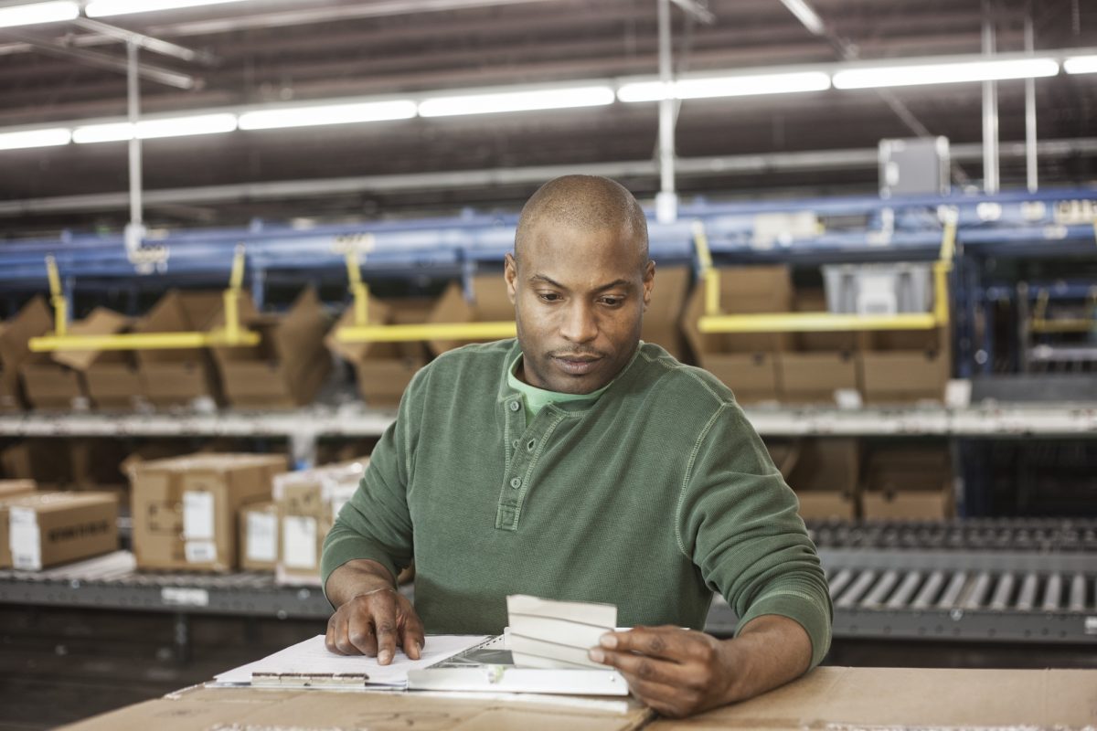 Working portrait of an African American warehouse worker in a large distribution warehouse.